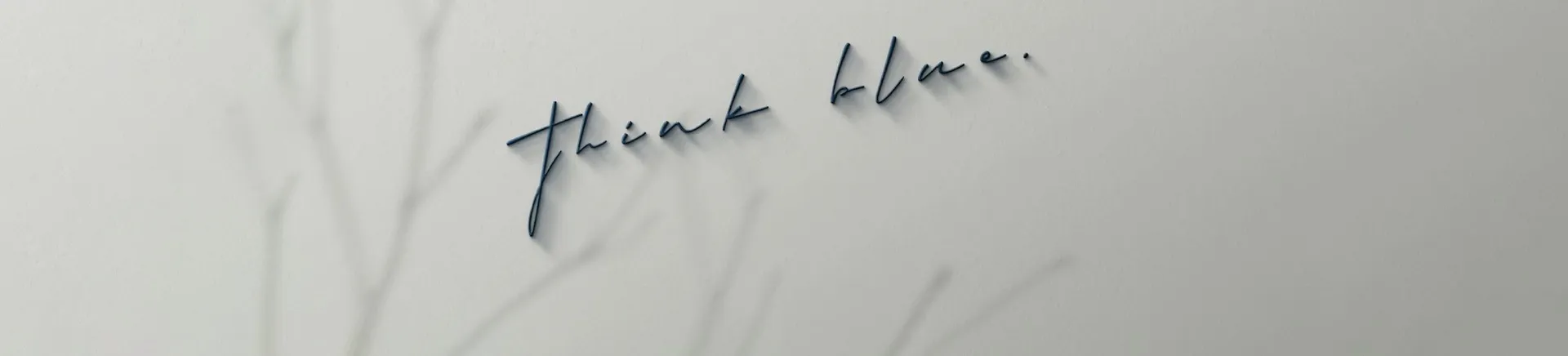 “think blue” written in navy script on a pale wall